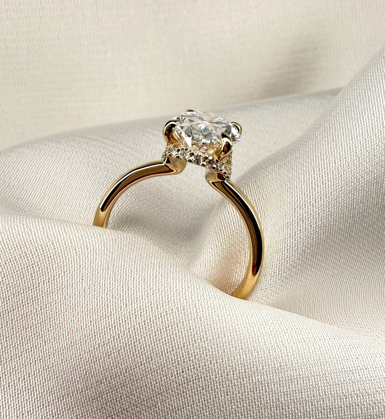 Gold ring with a diamond on a beige fabric background