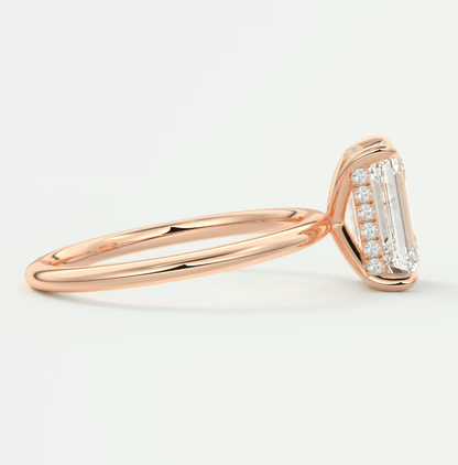 18k rose gold engagement ring with emerald-cut diamond and small diamonds on the band.