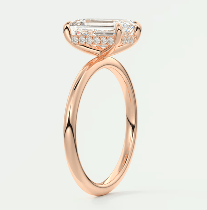 18k rose gold engagement ring with a baguette-cut diamond and smaller diamonds set in the band.