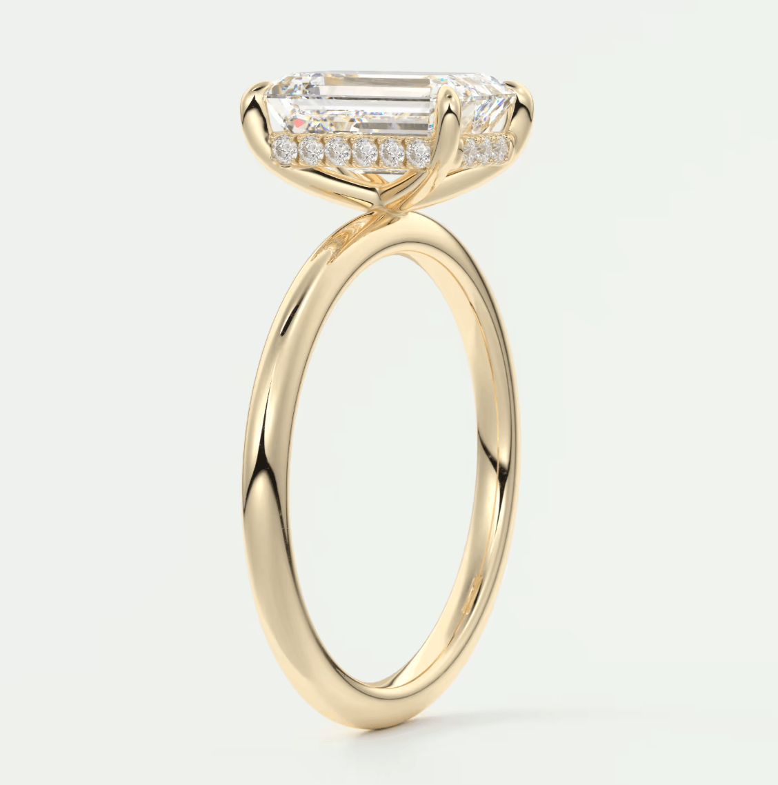 18k yellow gold engagement ring with emerald-cut diamond center stone and pavé diamonds on the band.