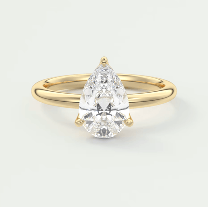 Pear-shaped diamond engagement ring with gold band and prong setting.
