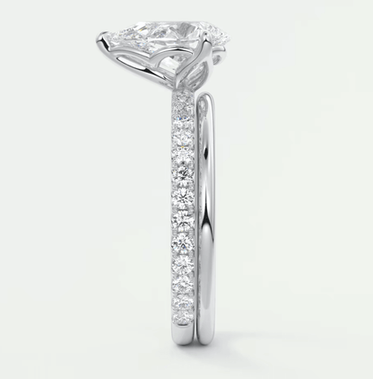 18-karat white gold engagement ring with a cushion-cut diamond center stone and pavé-set diamonds on the band.