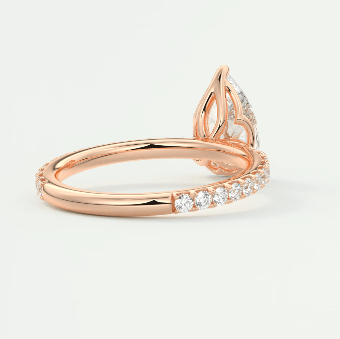 Rose gold diamond engagement ring with a pear-shaped center stone and pave set diamonds on the band.
