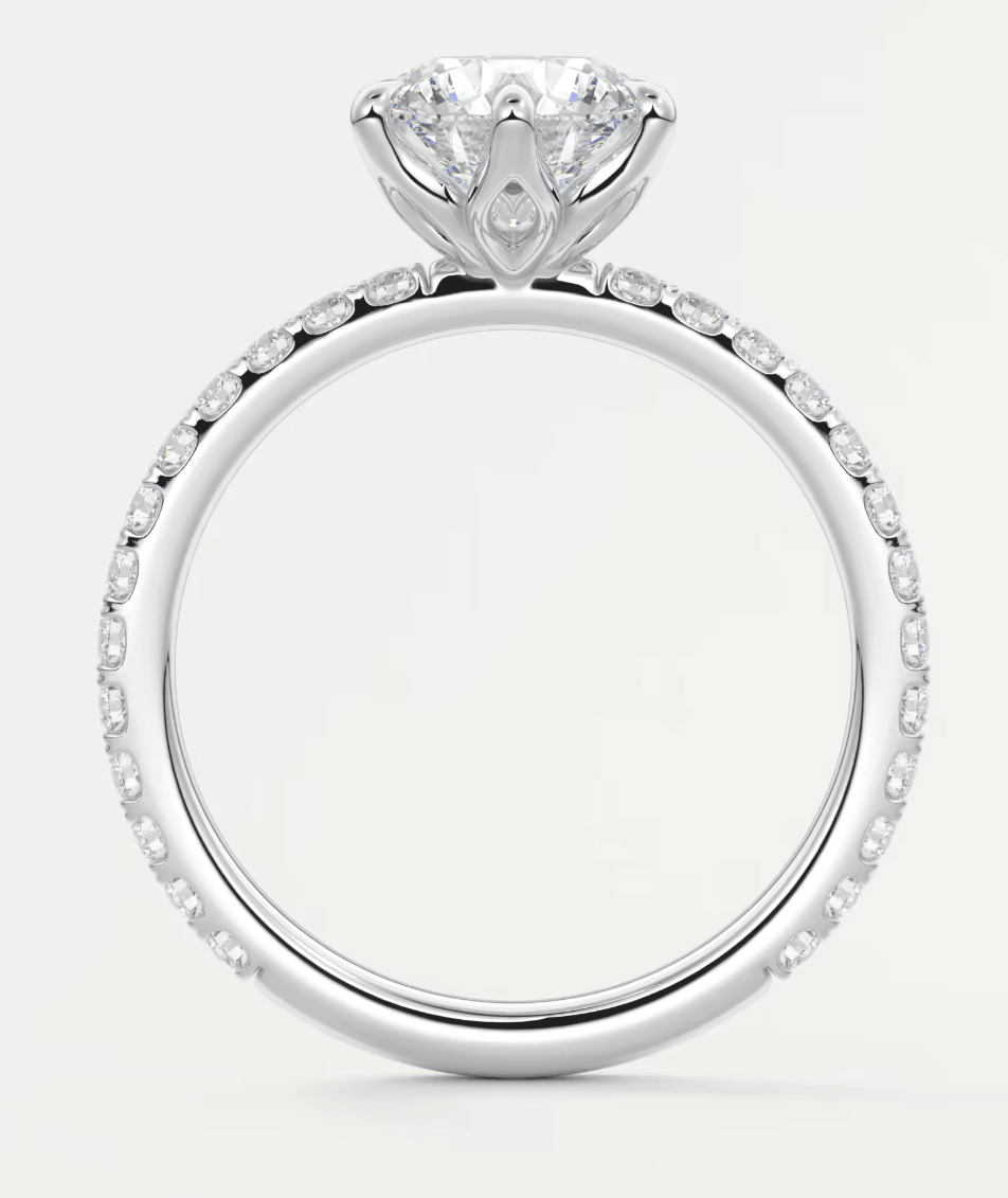 18-karat white gold engagement ring with a round diamond center and pavé set diamonds along the band.