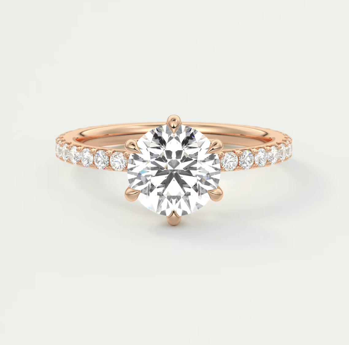 18-karat rose gold engagement ring with a round diamond center and pavé-set diamonds on the band.