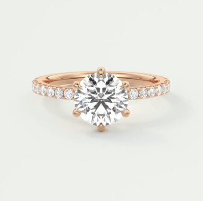18-karat rose gold engagement ring with a round diamond center and pavé-set diamonds on the band.