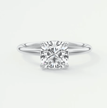Cushion-cut diamond engagement ring with white gold band, featuring a central stone and four prongs.
