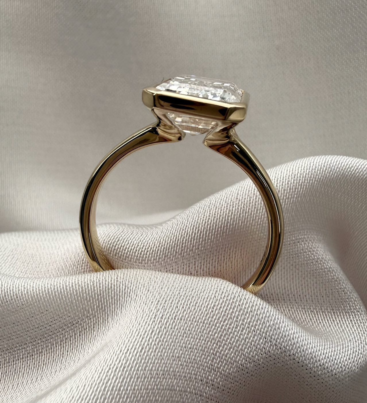 Gold ring with a diamond on a white fabric background