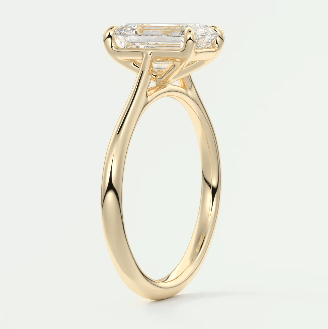 18k yellow gold engagement ring with a rectangular diamond center and baguette diamonds on the band.