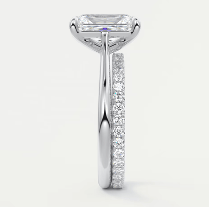 18-karat white gold engagement ring with an emerald-cut diamond center stone and a pave set band.
