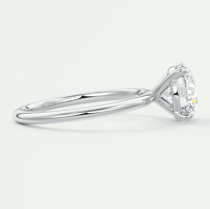 18k white gold diamond engagement ring with a round-cut center stone and small side diamonds.