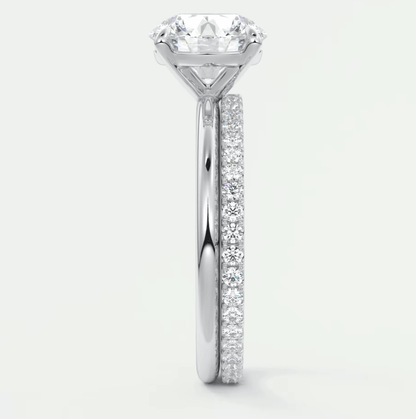 18k white gold engagement ring with a round diamond center stone and pave set diamonds on the band.