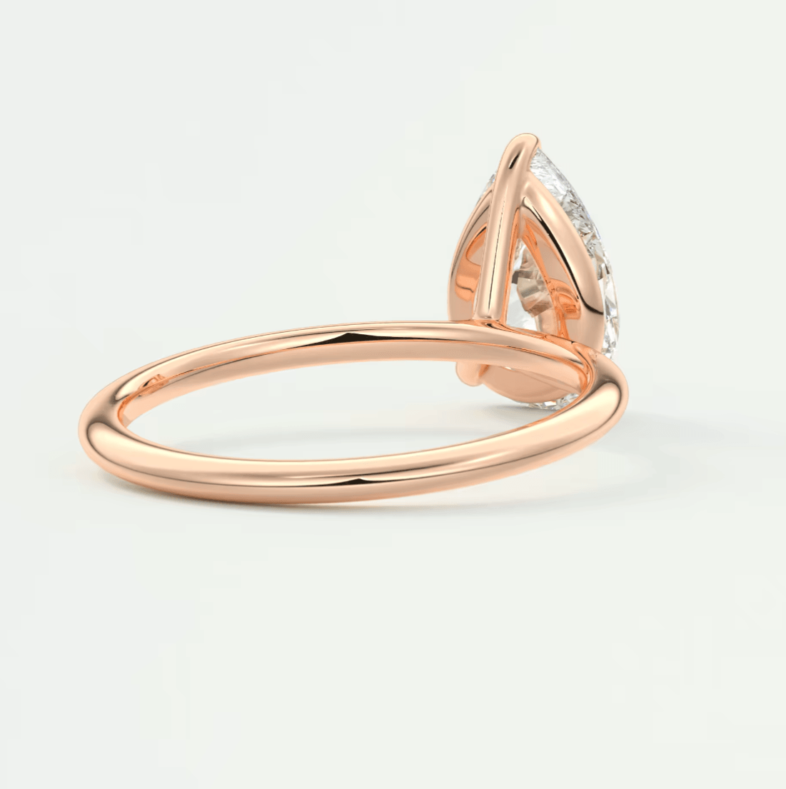 Rose gold pear-shaped diamond engagement ring with a halo design.