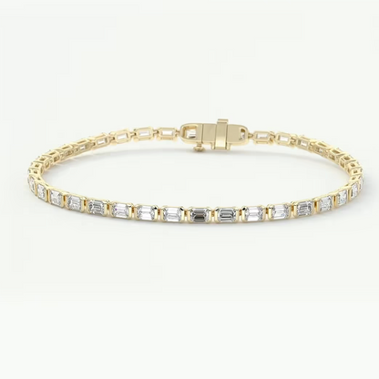 A yellow gold tennis bracelet featuring a row of baguette-cut clear gemstones, displayed on a clean white background.