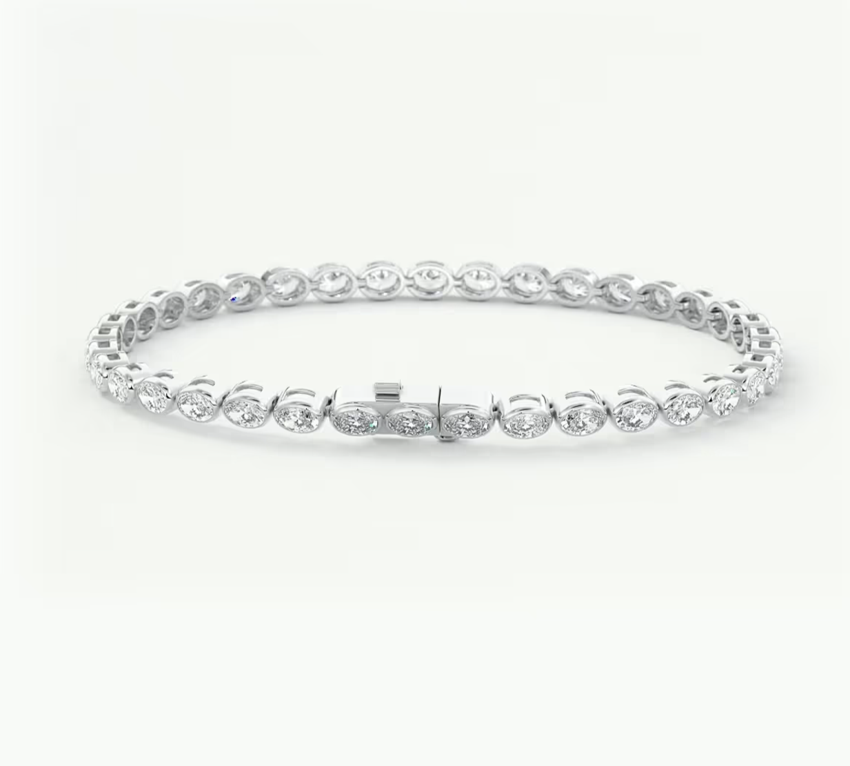 A platinum tennis bracelet with oval-cut clear gemstones in a classic link design, displayed on a clean white background.