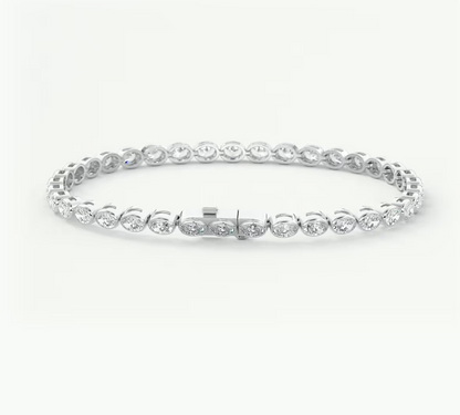 A platinum tennis bracelet with oval-cut clear gemstones in a classic link design, displayed on a clean white background.