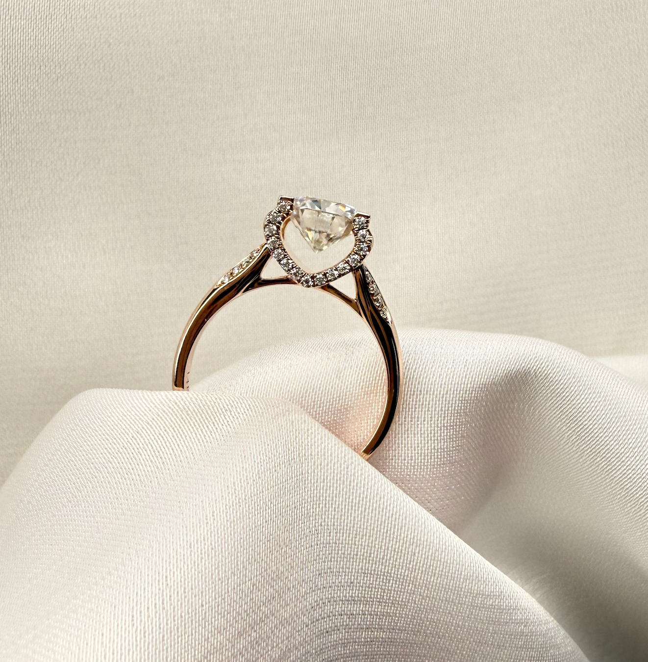 Diamond ring on a white fabric surface with a neutral background