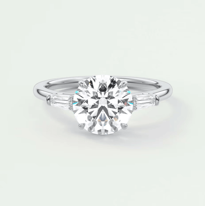 18k white gold engagement ring with a round diamond center and baguette diamonds on the band.