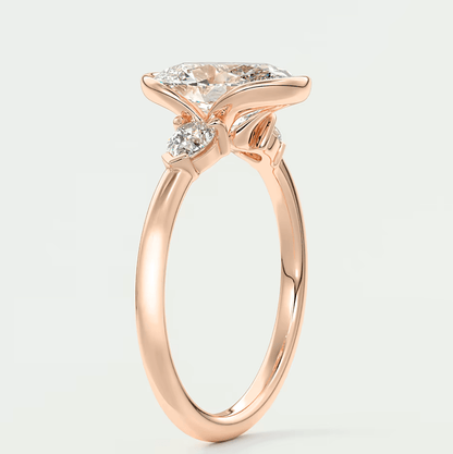 Rose gold diamond engagement ring with a marquise-cut center stone and two smaller diamonds on each side.