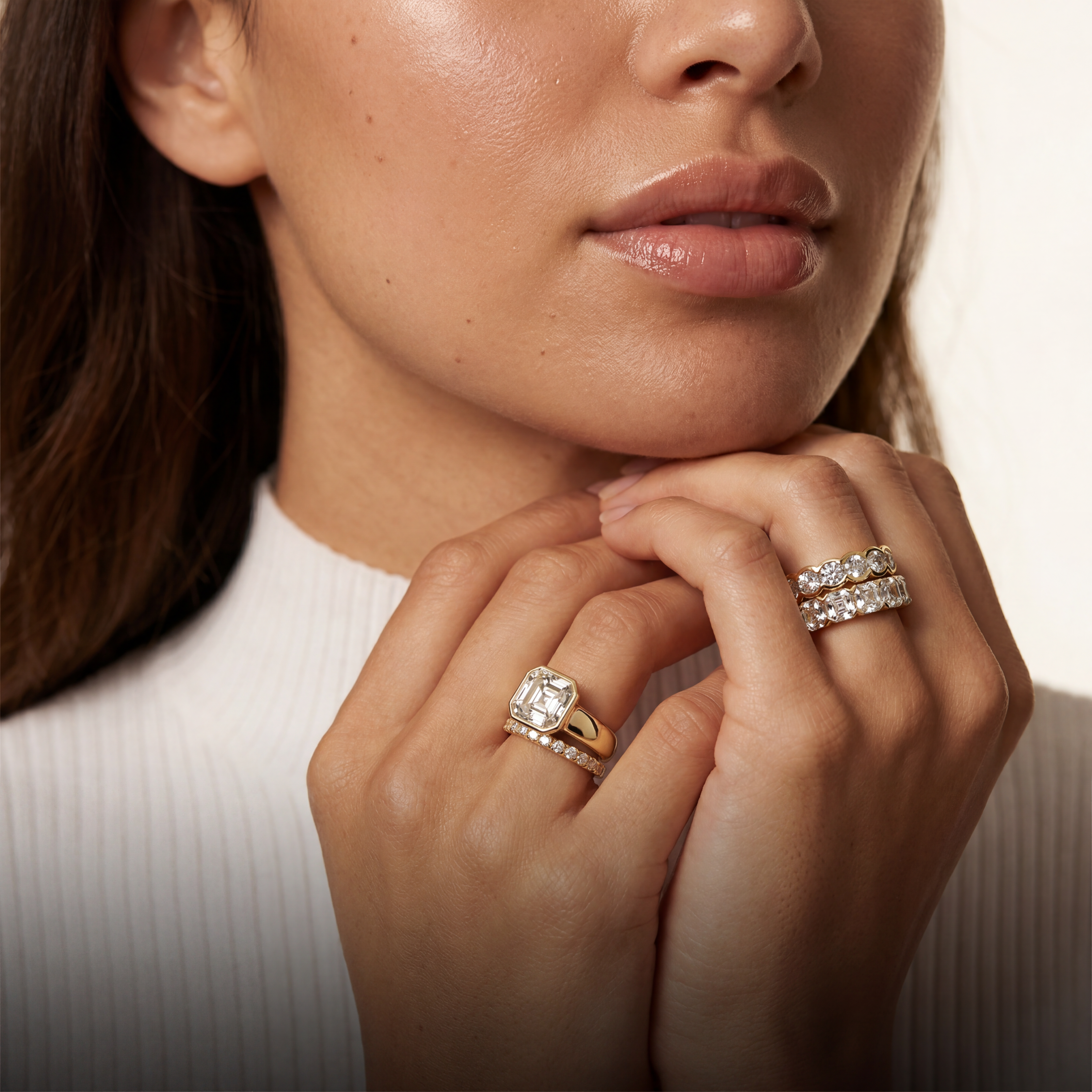 Close-up of a woman's hands wearing two diamond rings with a neutral background