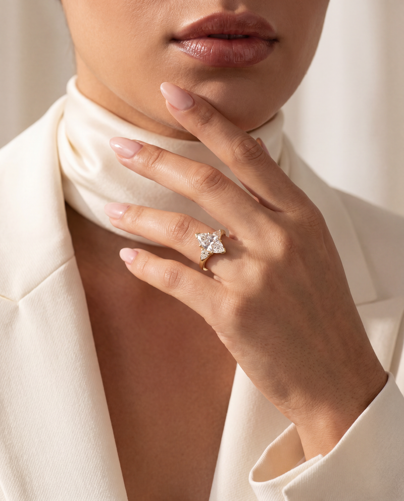 A close-up lifestyle shot of a model wearing a silver-toned ring with a star-shaped clear gemstone cluster on her finger, styled with a cream satin neck scarf and a cream blazer.