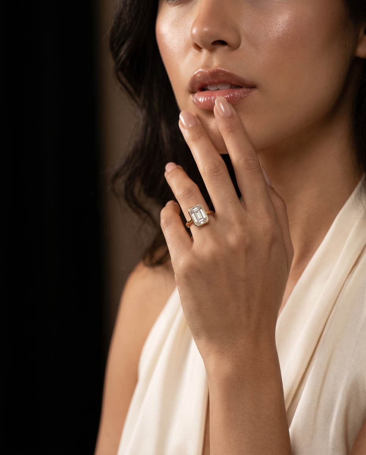 Woman wearing a diamond ring on her finger with a neutral background