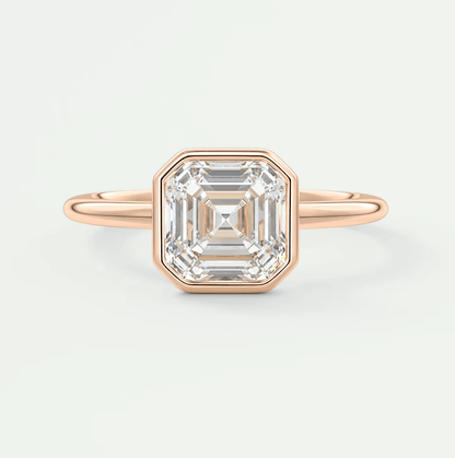 18k rose gold emerald cut diamond ring with a bezel setting.