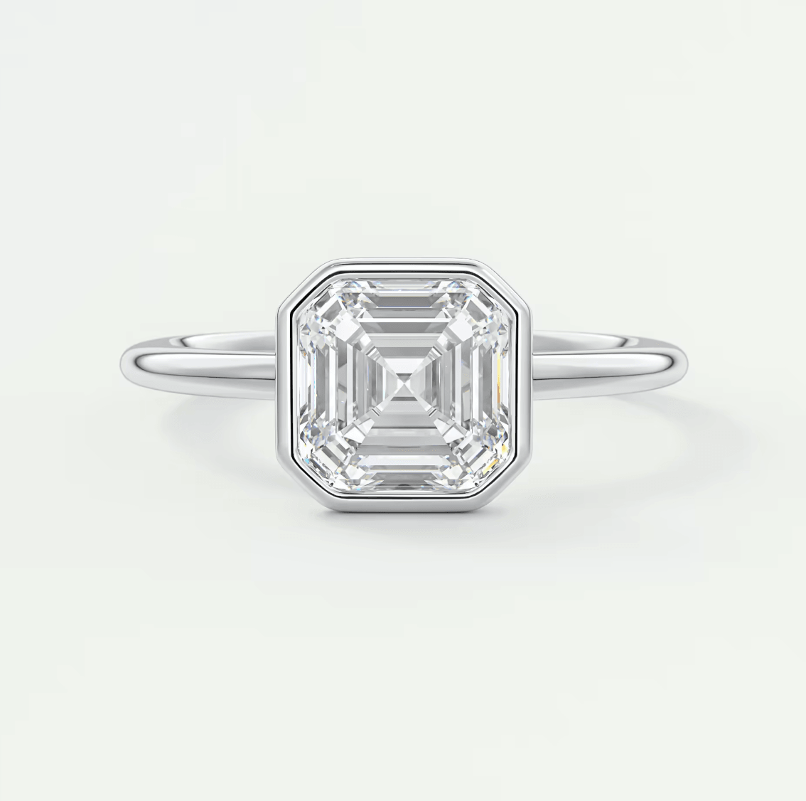 18k white gold emerald cut diamond engagement ring with a bezel setting.