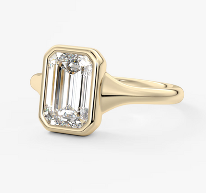 18k yellow gold emerald-cut diamond ring with a bezel setting.