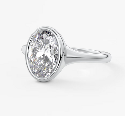 18-karat white gold diamond engagement ring with a bezel setting.
