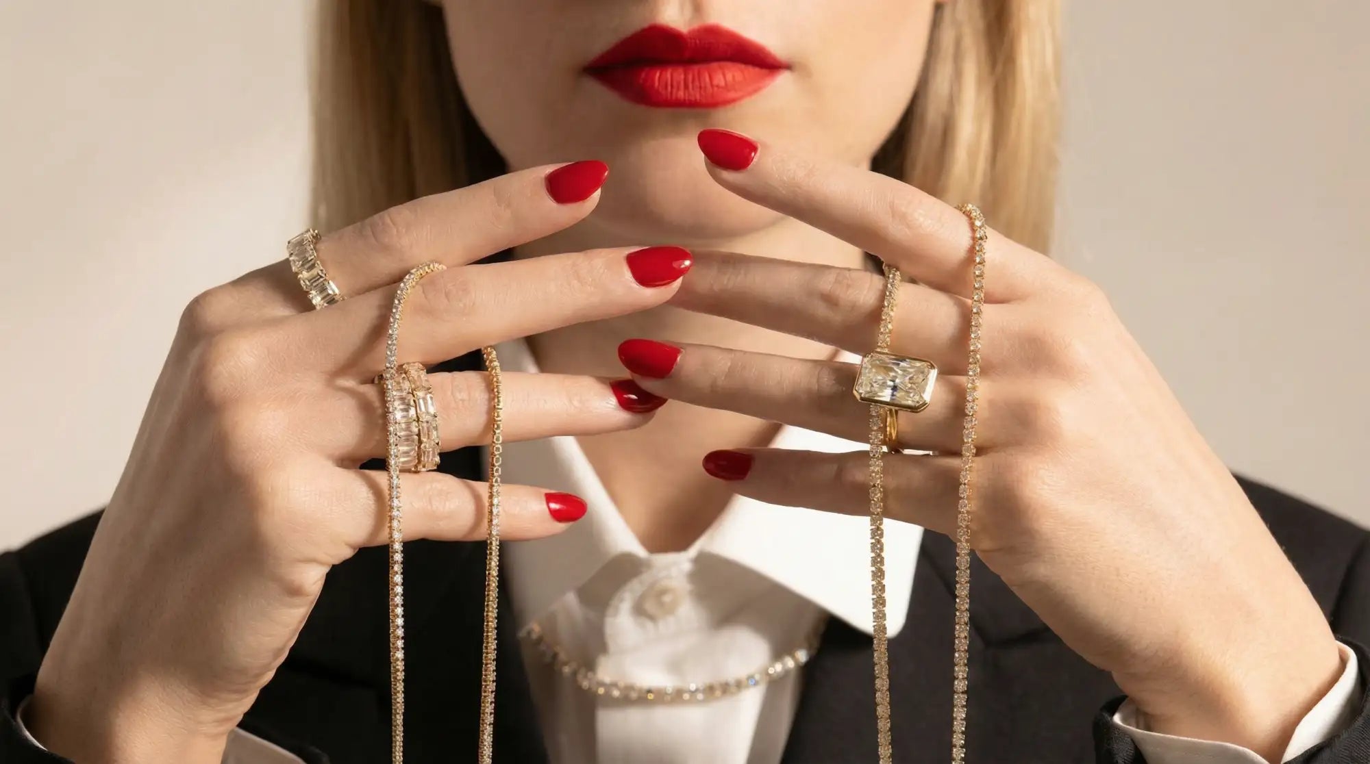 Close-up of a woman's hands with red nail polish wearing multiple rings.