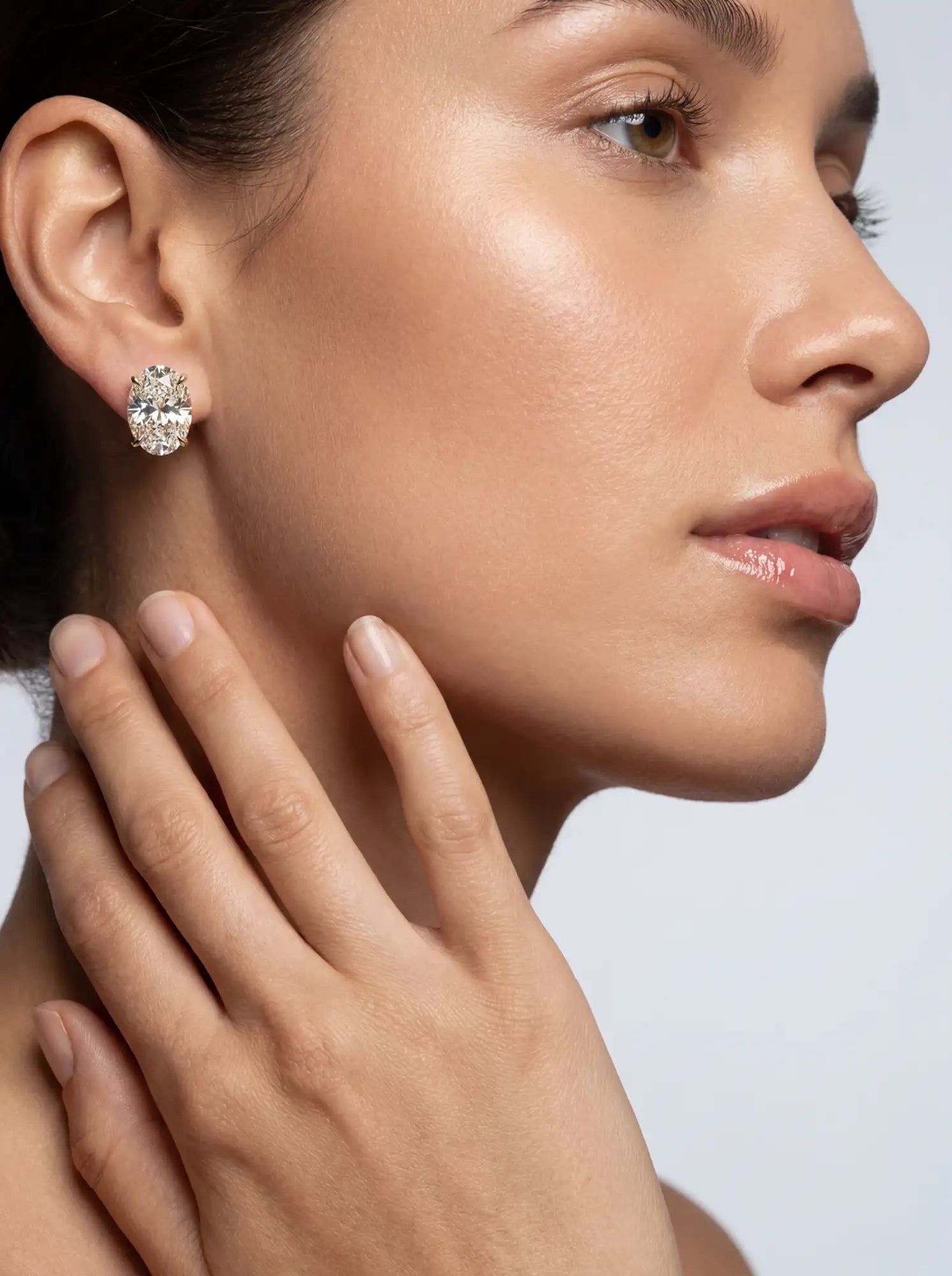 Close-up of a woman wearing a diamond earring with a neutral background