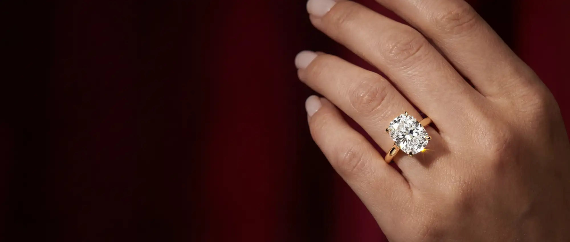 Hand wearing a diamond ring on a dark background