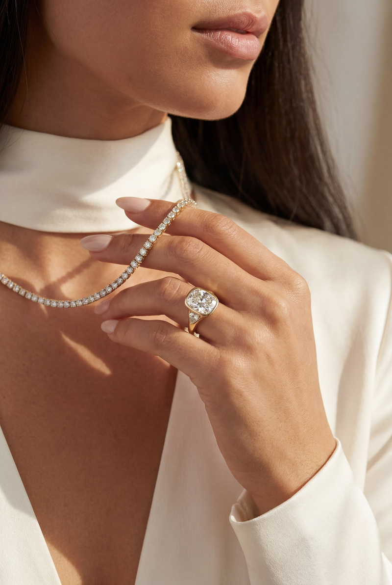 Close-up of a woman wearing a diamond ring and pearl necklace against a neutral background