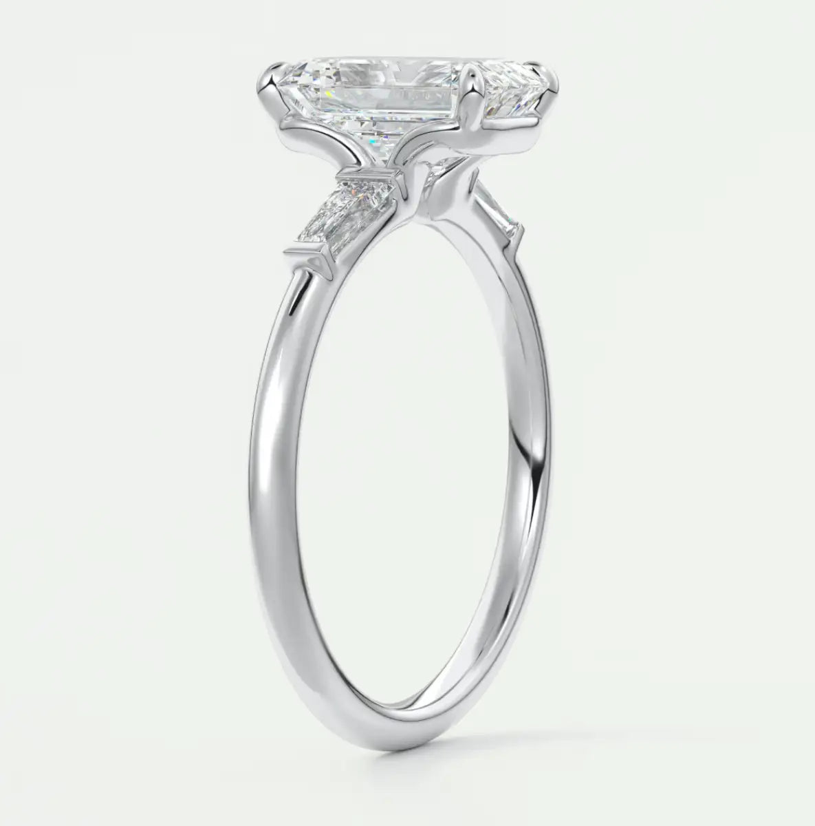 Custom made elysian emerald three-stone engagement ring with tapered baguettes