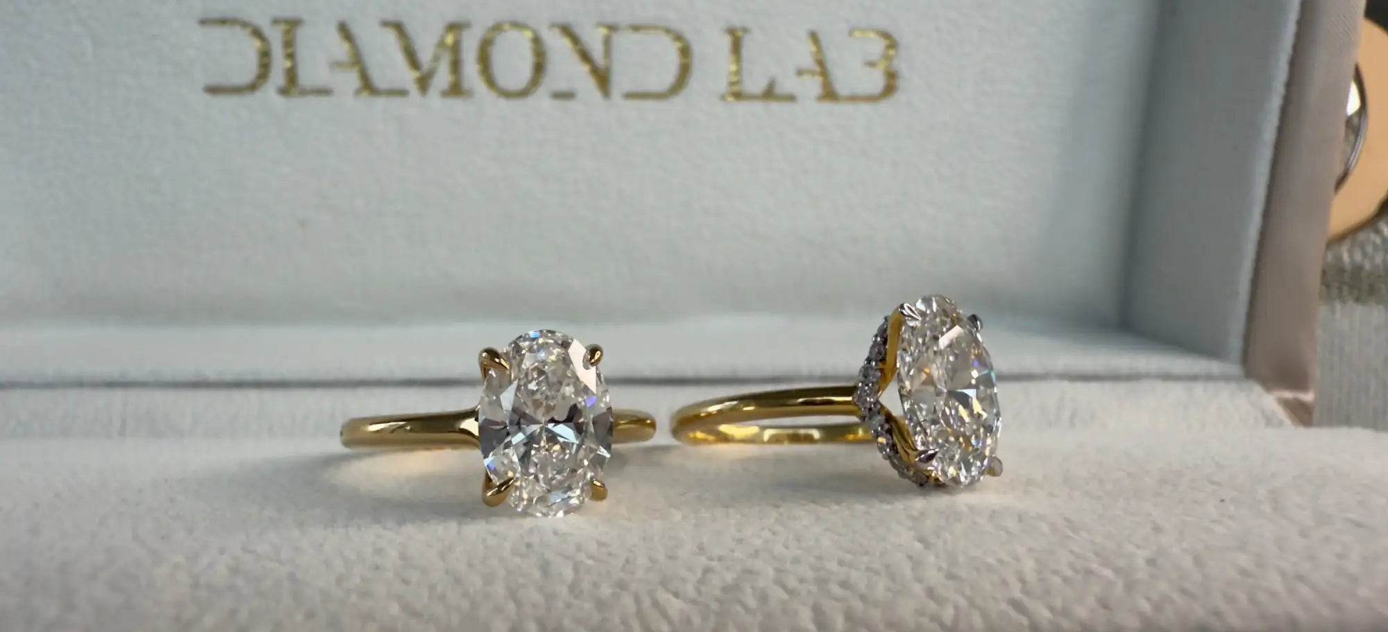 Two diamond rings on a cushioned surface with 'Diamond Lab' branding.