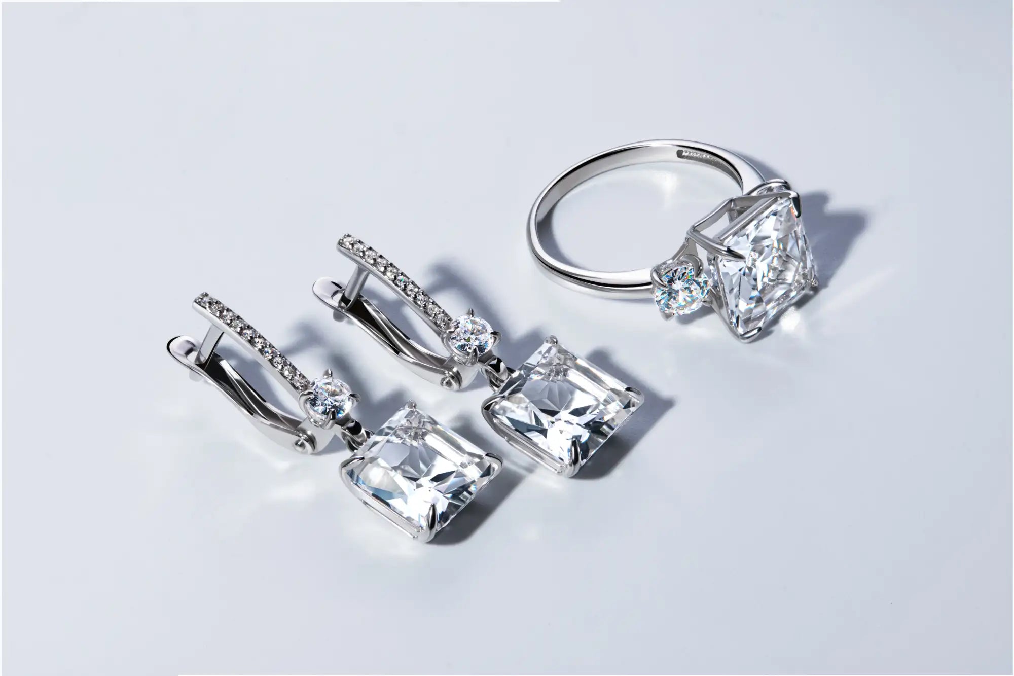 Silver ring and earrings with clear gemstones on a light gray background