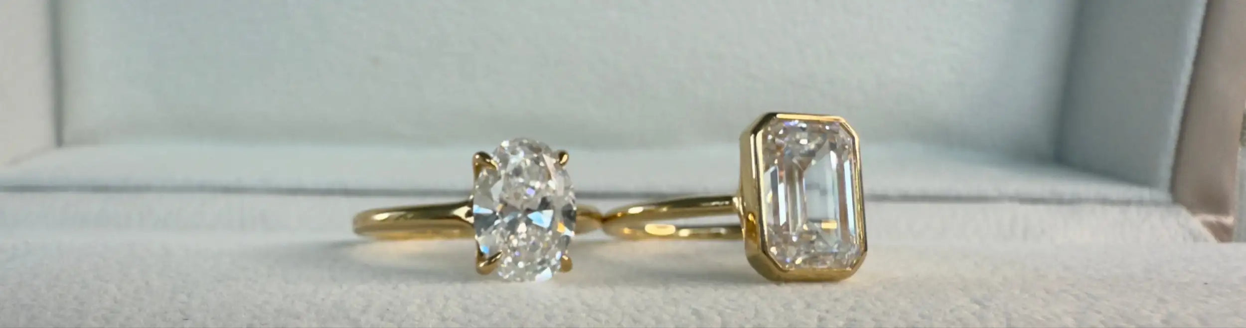 Two gold rings with diamond stones on a 'Diamond Lab' branded box.
