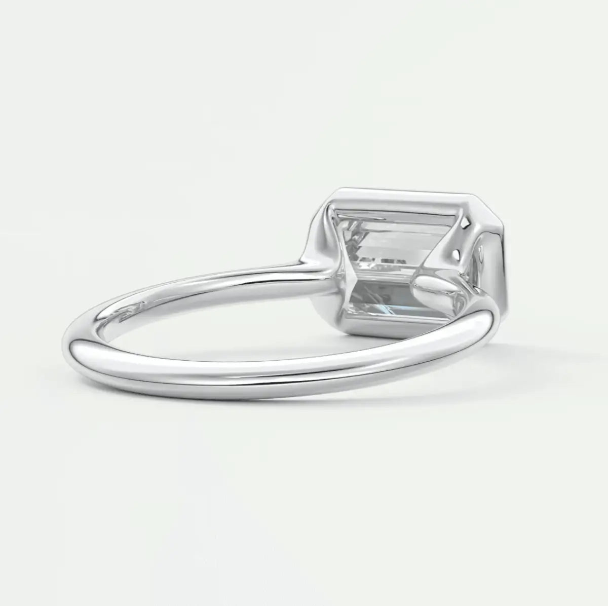 White gold emerald cut diamond engagement ring with a princess-cut center stone.
